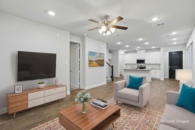 living area featuring light wood-type flooring, baseboards, stairs, and recessed lighting