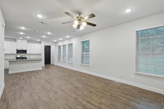 unfurnished living room with ceiling fan, baseboards, dark wood finished floors, and recessed lighting