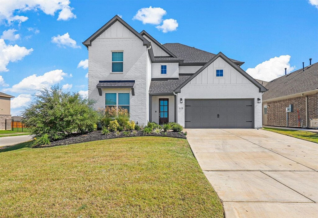 modern farmhouse featuring driveway, a front yard, brick siding, board and batten siding, and a shingled roof