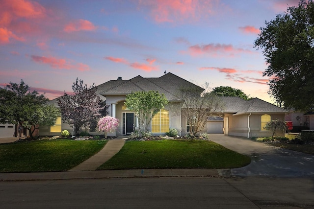 view of front of house featuring stucco siding, a yard, and driveway