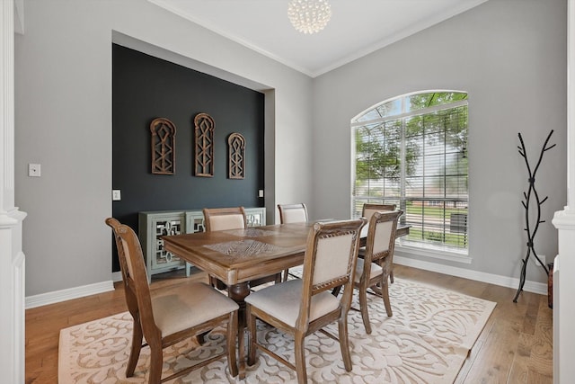 dining area with a chandelier, ornamental molding, a wealth of natural light, and wood finished floors