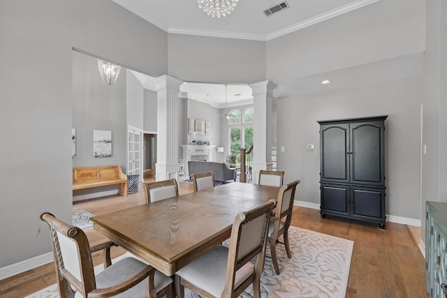 dining space featuring visible vents, an inviting chandelier, decorative columns, baseboards, and a high ceiling