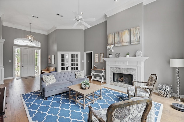 living room featuring visible vents, ornamental molding, wood finished floors, and a towering ceiling