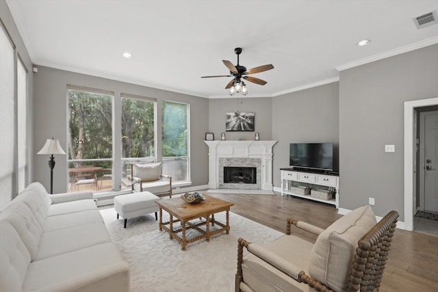 living room featuring visible vents, crown molding, wood finished floors, a fireplace, and ceiling fan