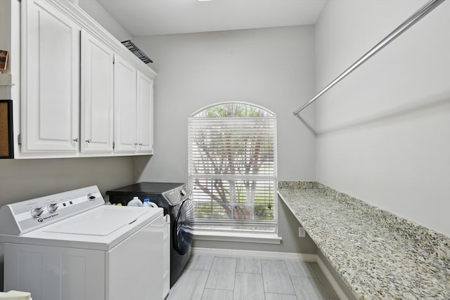 clothes washing area with cabinet space, baseboards, and washing machine and dryer