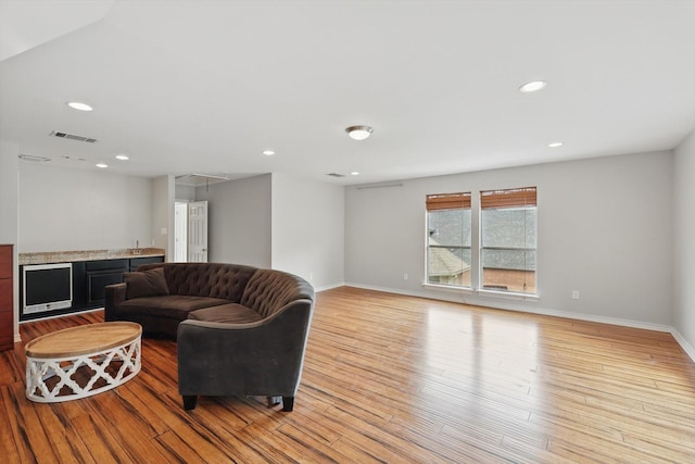 living area featuring visible vents, baseboards, attic access, light wood-style floors, and recessed lighting
