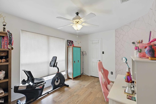 exercise room with ceiling fan and light wood-type flooring