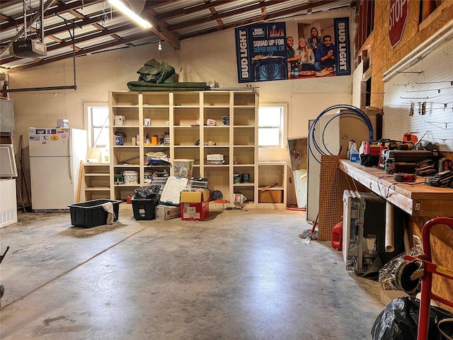 109 Bluebonnet Dr, Whitney, TX 76692 - garage featuring freestanding refrigerator, a garage door opener, and a workshop area