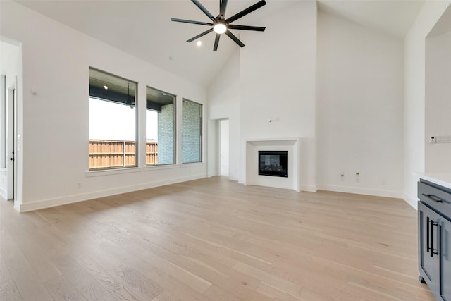 814 Montrose Dr, Rockwall, TX 75087 - unfurnished living room with ceiling fan, light wood-style floors, a glass covered fireplace, high vaulted ceiling, and baseboards