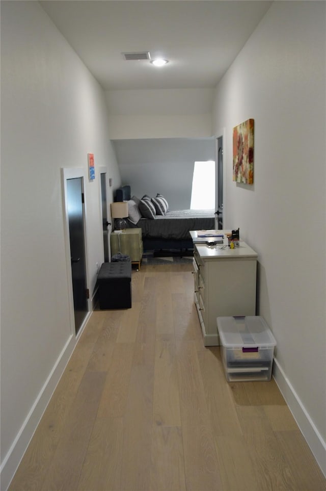hall featuring baseboards, visible vents, and light wood-style flooring