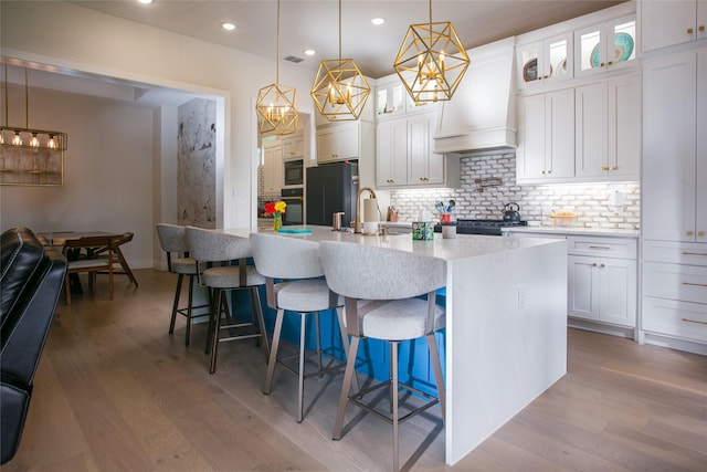 2519 Tamaron Cv, Cedar Hill, TX 75104 - kitchen with black appliances, tasteful backsplash, a center island with sink, light wood-type flooring, and recessed lighting