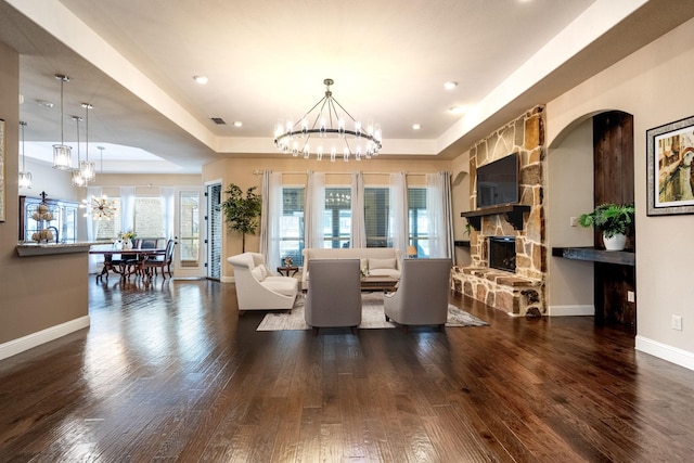living area with a fireplace, wood finished floors, and a notable chandelier