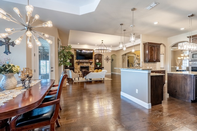 kitchen with arched walkways, visible vents, a notable chandelier, and a fireplace