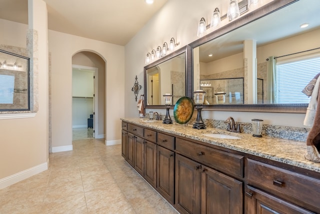 bathroom with tile patterned floors, a sink, double vanity, and a stall shower