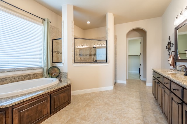 full bath featuring baseboards, a bath, vanity, and tiled shower