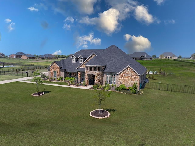 view of front of property featuring driveway, stone siding, a front lawn, and fence