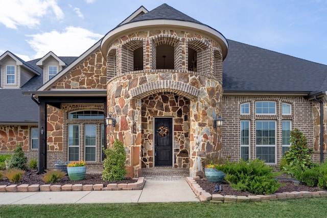 property entrance featuring brick siding, stone siding, and a shingled roof