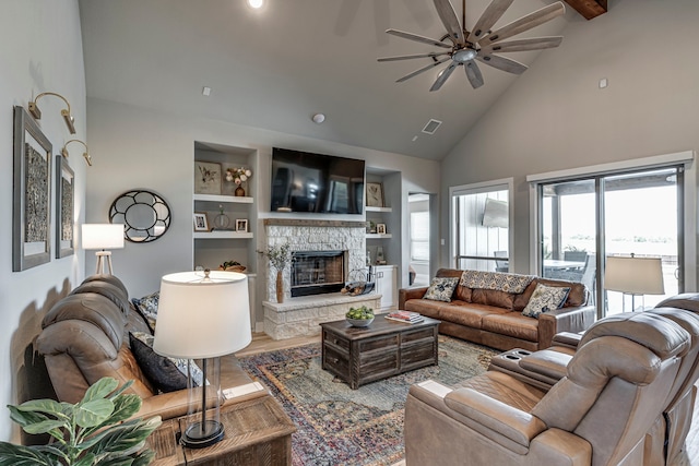 living room with high vaulted ceiling, visible vents, a fireplace, built in shelves, and a ceiling fan