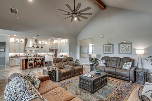 living room with light wood-type flooring, a ceiling fan, beamed ceiling, and visible vents