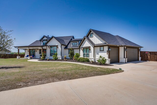 modern farmhouse style home with a garage, fence, a front lawn, and board and batten siding