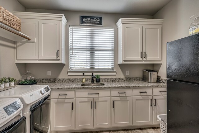 kitchen featuring freestanding refrigerator, independent washer and dryer, a sink, and white cabinets