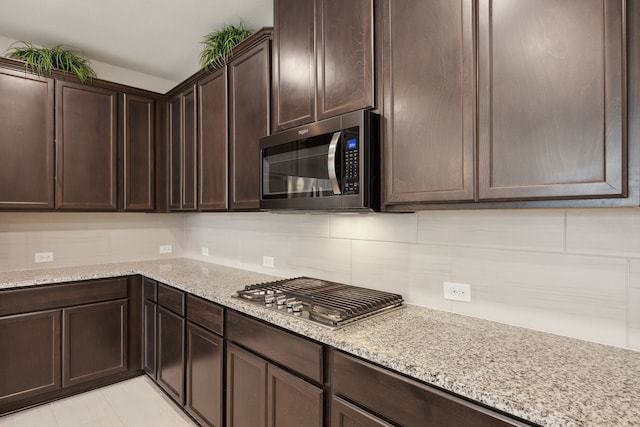 9814 Gristmill Ln, Frisco, TX 75035 - kitchen featuring dark brown cabinetry, tasteful backsplash, light stone countertops, and stainless steel appliances