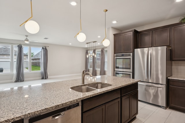 9814 Gristmill Ln, Frisco, TX 75035 - kitchen featuring dark brown cabinets, hanging light fixtures, a sink, stainless steel appliances, and light stone countertops
