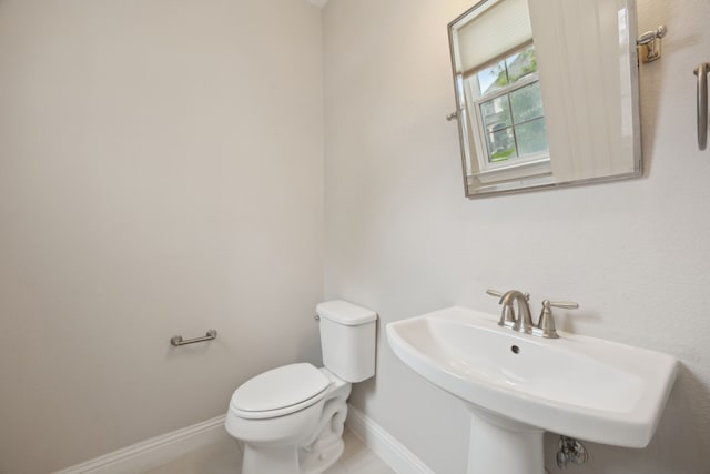 9814 Gristmill Ln, Frisco, TX 75035 - half bathroom featuring baseboards, toilet, a sink, and tile patterned floors