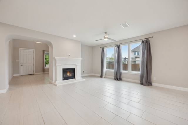 9814 Gristmill Ln, Frisco, TX 75035 - unfurnished living room with a ceiling fan, a glass covered fireplace, arched walkways, visible vents, and recessed lighting