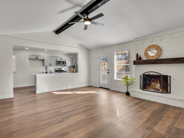 unfurnished living room with a sink, baseboards, a ceiling fan, and wood finished floors