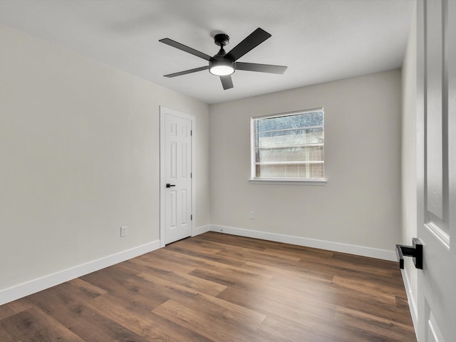 empty room with baseboards, dark wood-style floors, and ceiling fan