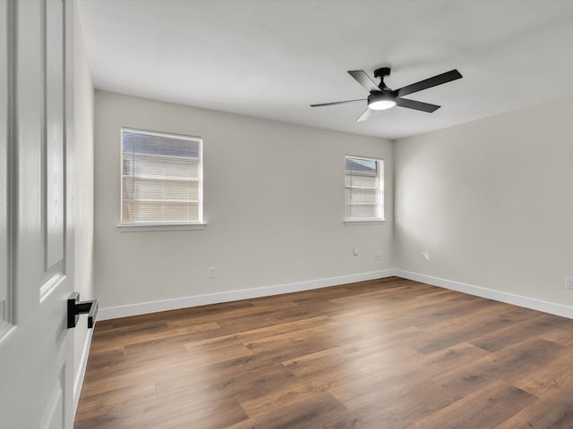 unfurnished room with baseboards, ceiling fan, and dark wood-style floors