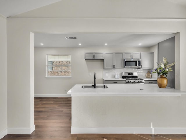 6916 Bennington Dr, Watauga, TX 76148 - kitchen with appliances with stainless steel finishes, a sink, gray cabinetry, tasteful backsplash, and light countertops