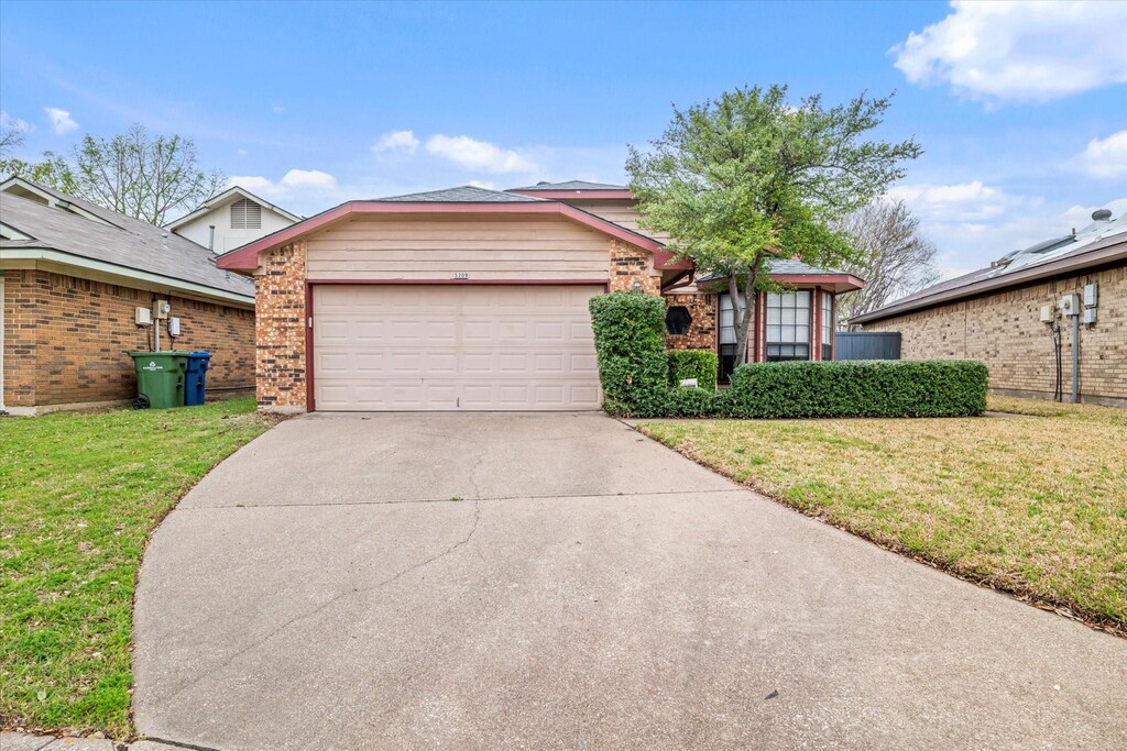 single story home featuring brick siding, a garage, concrete driveway, and a front yard