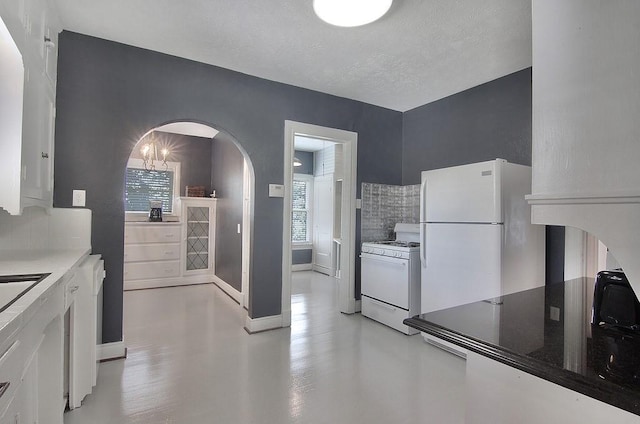 kitchen with backsplash, baseboards, white appliances, white cabinets, and arched walkways