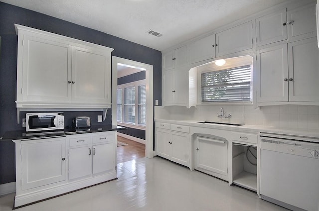 kitchen with white appliances, baseboards, white cabinetry, a sink, and backsplash