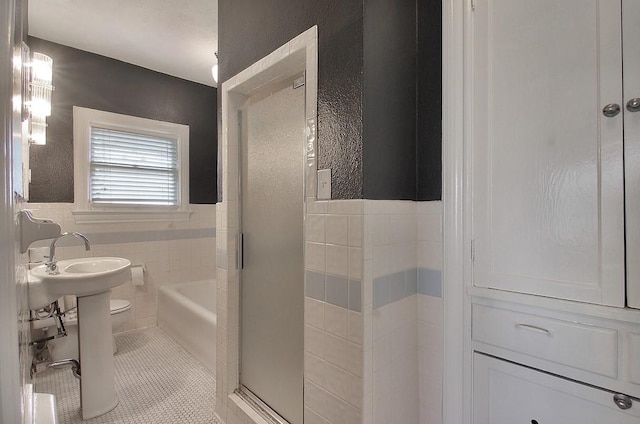 full bath with tile walls, a shower, toilet, tile patterned floors, and a tub