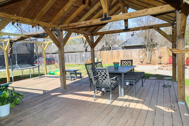502 Parklane Dr, Bossier City, LA 71111 - wooden deck featuring a trampoline, a fenced backyard, and outdoor dining space