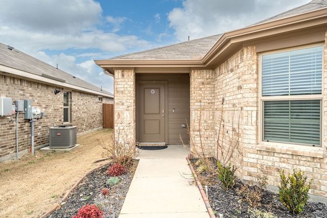 16617 Porterfield Ln, Justin, TX 76247 - view of exterior entry featuring central AC unit, fence, a shingled roof, and brick siding