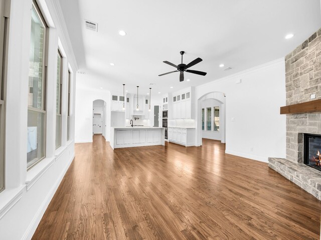 145 Fan Mill Trl, Weatherford, TX 76085 - unfurnished living room featuring arched walkways, visible vents, a ceiling fan, a fireplace, and wood finished floors