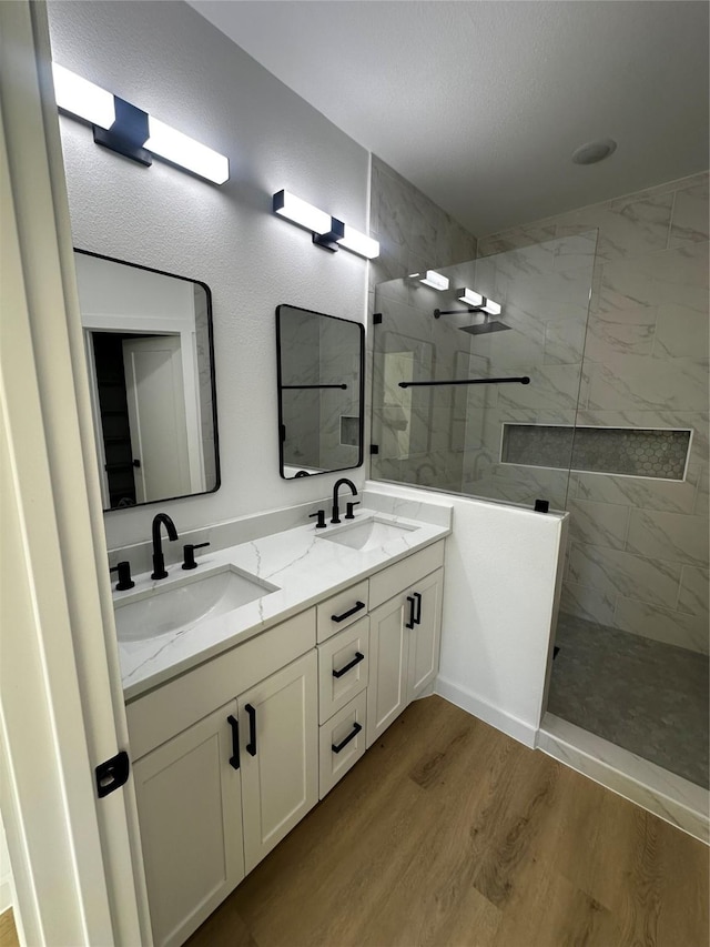 full bath featuring double vanity, a sink, and a marble finish shower