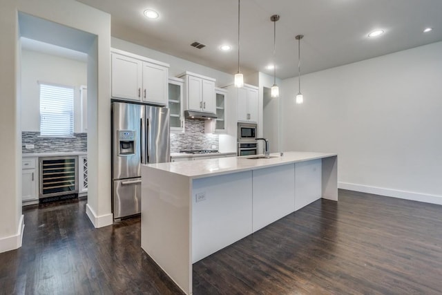 3023 Clamath Dr, Dallas, TX 75204 - kitchen featuring wine cooler, appliances with stainless steel finishes, under cabinet range hood, decorative backsplash, and recessed lighting