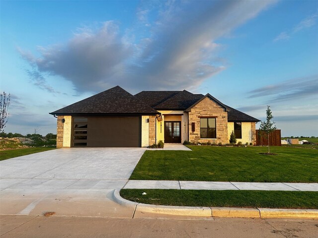 prairie-style house featuring french doors, a front lawn, brick siding, an attached garage, and a shingled roof