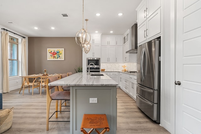 1065 Manacor Ln, Dallas, TX 75212 - kitchen featuring appliances with stainless steel finishes, wall chimney exhaust hood, a breakfast bar area, backsplash, and light stone countertops