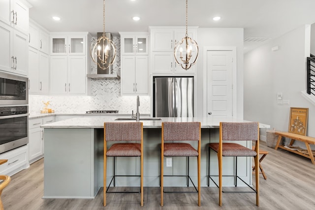 1065 Manacor Ln, Dallas, TX 75212 - kitchen featuring appliances with stainless steel finishes, a sink, a chandelier, decorative backsplash, and a center island with sink