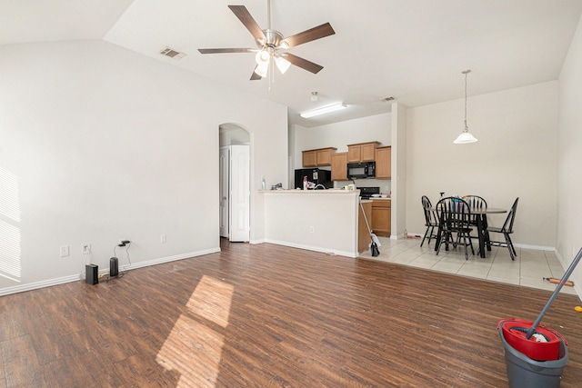 living room with light wood finished floors, a ceiling fan, visible vents, and arched walkways