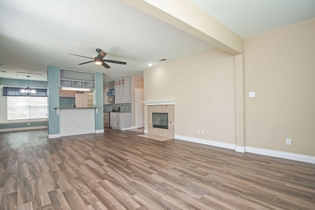 12073 Tyler Dr, Frisco, TX 75035 - unfurnished living room featuring wood finished floors, a ceiling fan, a tiled fireplace, and baseboards
