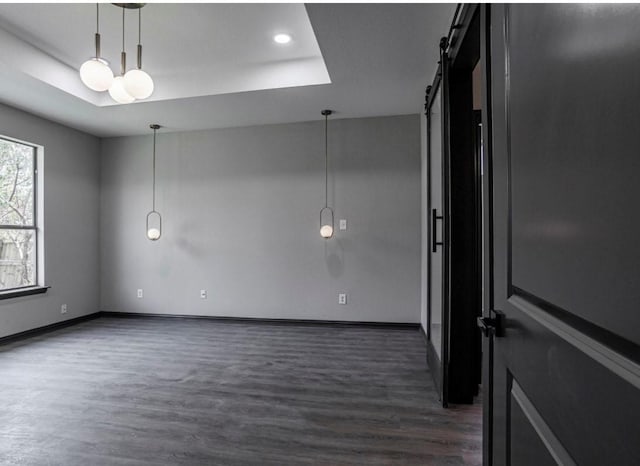 6609 Rockdale Rd, Fort Worth, TX 76134 - spare room with dark wood-type flooring, a barn door, a tray ceiling, and baseboards