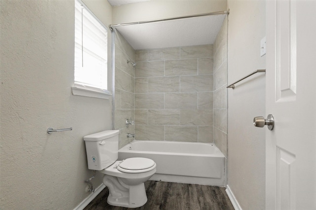 bathroom featuring wood finished floors, a textured wall, toilet, shower / bathtub combination, and baseboards