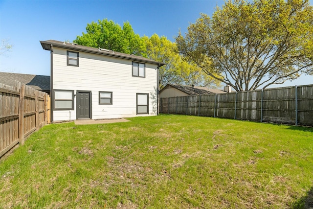 rear view of house with a lawn and a fenced backyard